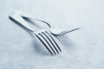 Two silver forks on marble background. Close-up. Copy space