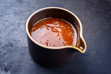 Modern style traditional hot sauce with cayenne peppers and vinegar as Louisiana style for smoked barbecue beef briskets as ingredient served as close-up in a design bowl