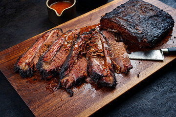 Modern style traditional smoked barbecue wagyu beef brisket served as top view on a wooden design...