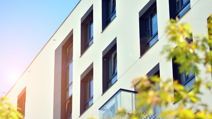 Obraz premium Ecological housing architecture. A modern residential building in the vicinity of trees. Ecology and green living in city, urban environment concept. Modern apartment building and green trees.