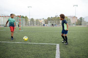 Little boy playing football. African American schoolboy at stadium. Young kids running outside. Happy black children practicing soccer. Training at field with ball. Exercise and healthy lifestyle