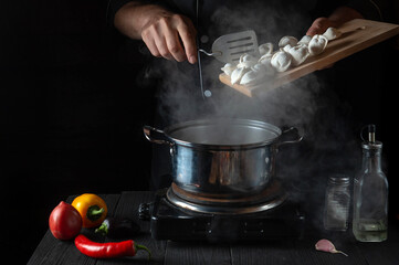 The chef cooks meat dumplings in a saucepan in the restaurant kitchen. Close-up of the hands of the cook during work. Free advertising space