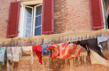Medieval windows in Italy, where Indian colored clothes are hung from a clothesline 