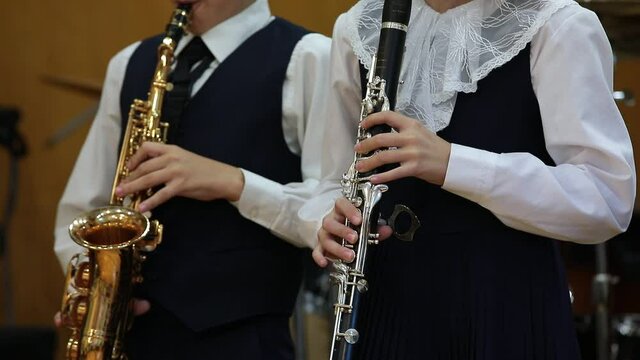 Children playing a musical instrument.Duet of young musicians college students boy with saxophone girl with clarinet performing at a concert hands close-up.School music education concept
