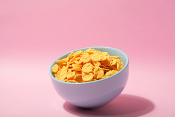 Delicious cornflakes in a plate against colored background. 