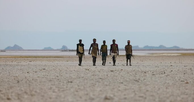 Group of Hadza hunter-gatherer tribesmen out hunting in barren landscape Tanzania