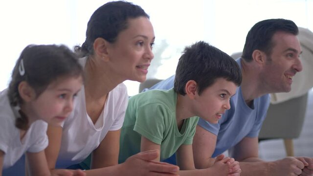 Close-up of smiling parents and preteen children standing in plank during yoga training. Cheerful family with little kids doing sports together, healthy lifestyle, bonding leisure activity concept