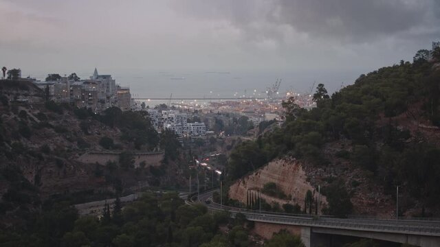 Timelapse of city harbor in the evening, cars driving on the highway and grey clouds moving quickly. 