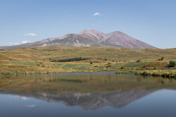 Naklejka premium Beautiful landscape. Yellow hills mountains and small lake and river under blue sky. 