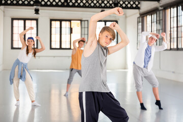 Teenage boy practicing hip hop moves with friends at group dance class