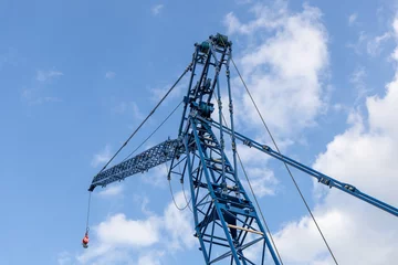 Fotobehang Lattice jib of a crawler crane against the blue sky, low viewing angle. Heavy equipment for construction, installation and repair work © hodim