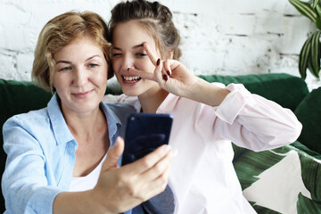 Obraz premium lifestyle, tehnology and people concept: mature mother and her daughter making a selfie using smart phone