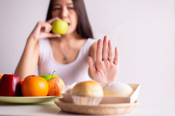 Obraz na płótnie Canvas Asian woman hands stop to bread and holding green apple on white background,Healthy diet,Dieting concept