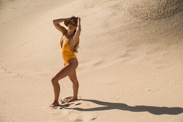 Fototapeta na wymiar sports woman in a swimsuit on the sand