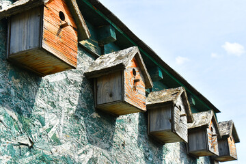 An image of old wooden hand made bird houses on a wooden granary. 
