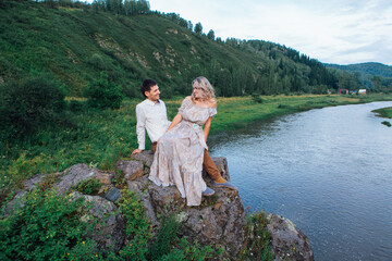 Romantic inloved couple sitting on rocks by the river.