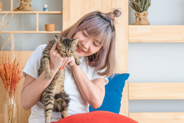 young woman playing with cat in living room at home