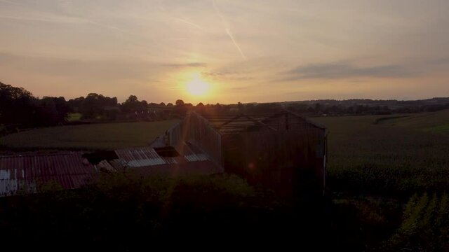 Silhouette Of Derelict Barn Against Sunset Skies. Aerial Pedestal Up