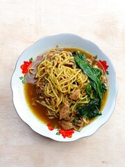 a plate of chicken noodles on the table made of plywood
