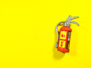 Toy fire extinguisher on a yellow background with copy space.