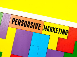 Business concept.Text PERSUASIVE MARKETING writing on wooden puzzle on a yellow background.