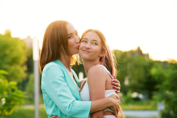 Mother Kissing on Cheek Smiling Teen Daughter. Enjoying moment and Having Fun Together. Candid Portrait Teenage Girl and Mom. Real People concept