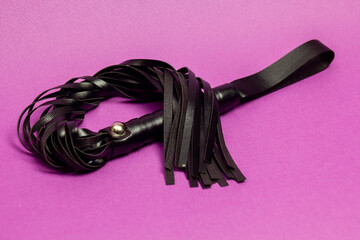 Leather whip on pink background