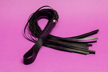 Leather whip on pink background