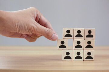 Man hands holding cube with many human symbol, leadership and corporate hierarchy concept.