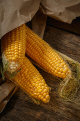 Fresh corn on the cob on a rustic wooden table, close up.