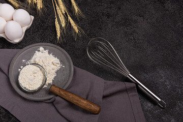 Dark background for baking with eggs, flour, wheat, whisk