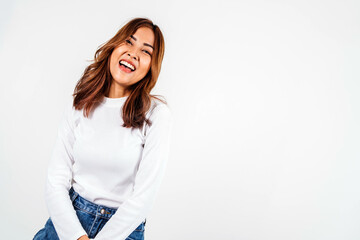 Asian dyed brown-haired girl in white sweater dancing with hands up and inspired face expression in white background.