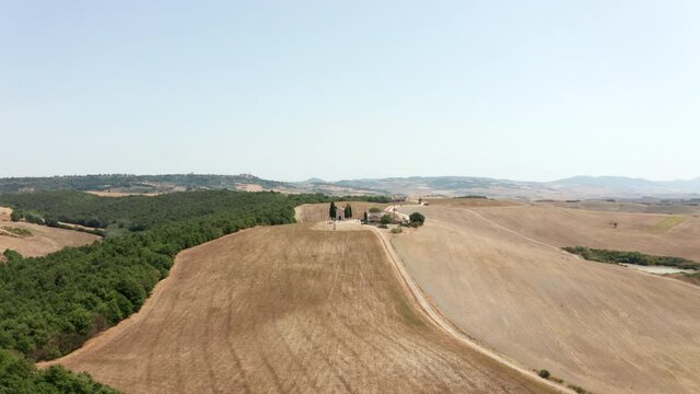 Drone clip, showing an old church in Tuscany, Italy, with beautiful agricultural fields surrounding it. Camera slowly rotating anti-clockwise.
