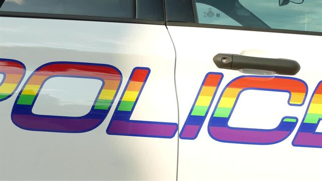 Closeup of a Pride police car with a rainbow paint pattern.