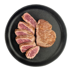 Fried cooked beef steak cut into pieces in a cast iron pan isolated on a white background.