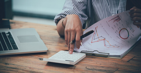 Close up business woman working on desk office with using a calculator to calculate the numbers, finance accounting concept.