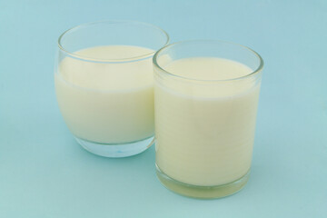 Two glasses of milk or cream on blue background