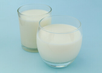 Glasses of milk or cream on blue background 