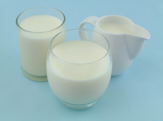 Jug with milk and two glasses of milk on blue background.	