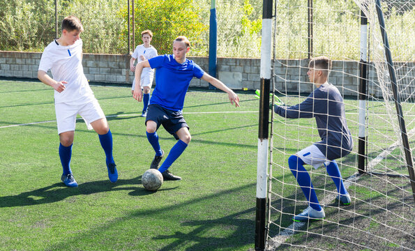 Junior football teams having golmouth scramble and struggling for ball