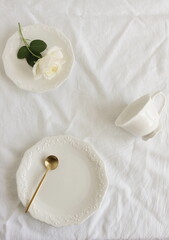 White ceramic coffee cup and sausers set top view on white linen tablecloth. Mockup classic porcelain utensils.Clean dishes for text . Business food brand template.