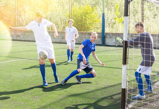 Junior football teams having golmouth scramble and struggling for ball