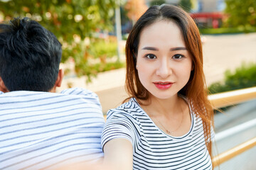 Fototapeta premium Beautiful positive young Asian woman taking selfie outdoors