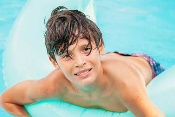 Happy holiday time. Boy having fun in pool with float. Face emotions. Summer vibes.