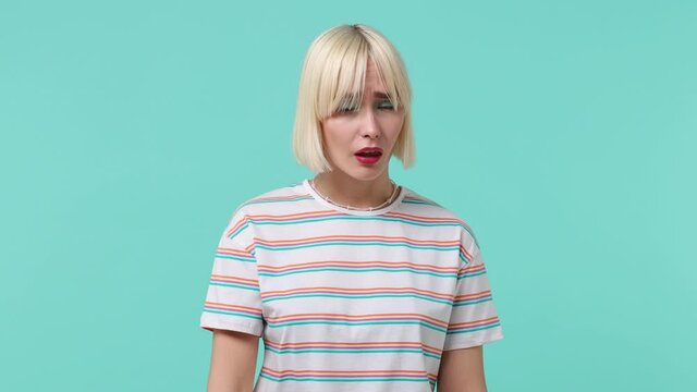 Tired young blonde short haircut woman 20s wears striped t-shirt did not get enough sleep last night barely got up in the morning yawning isolated on pastel plain light blue background studio portrait