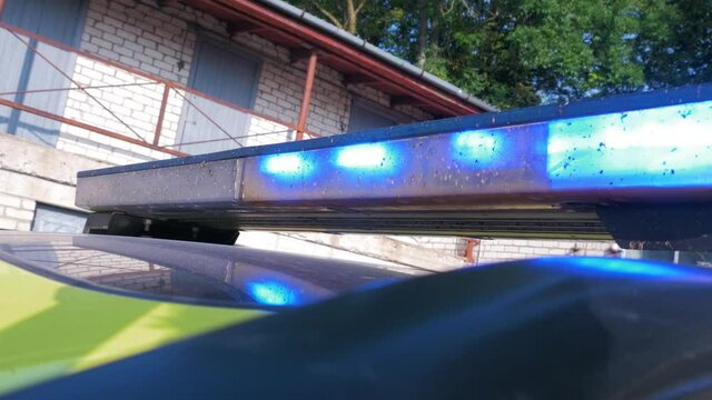 The roof of yellow paramedic ambulance vehicle with blue flashing warning lights, sunny day, handheld medium closeup shot