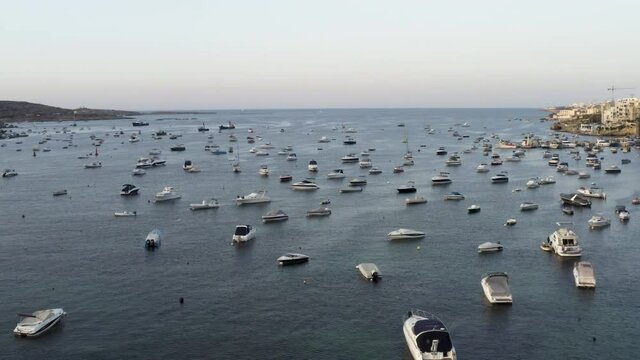 Aerial shot flying over hundreds of anchored yachts in a sea bay,Malta.