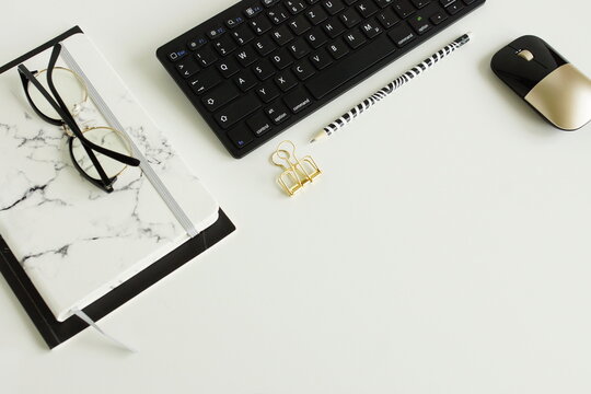 White office desk top view template with copy space.Minimal workspace with keyboard, glasses, notebooks. Black. white. gold color. Workplace of modern style .