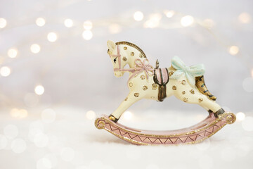 Vintage figurine of a rocking horse in sparkling lights on a white background. New Year's composition, place for text.