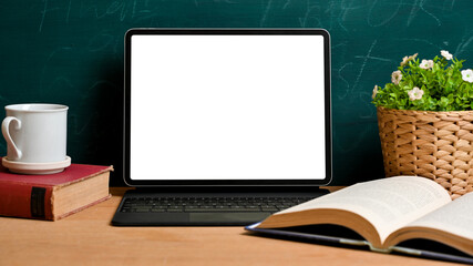 Tablet blank screen mockup with school decoration over green chalkboard